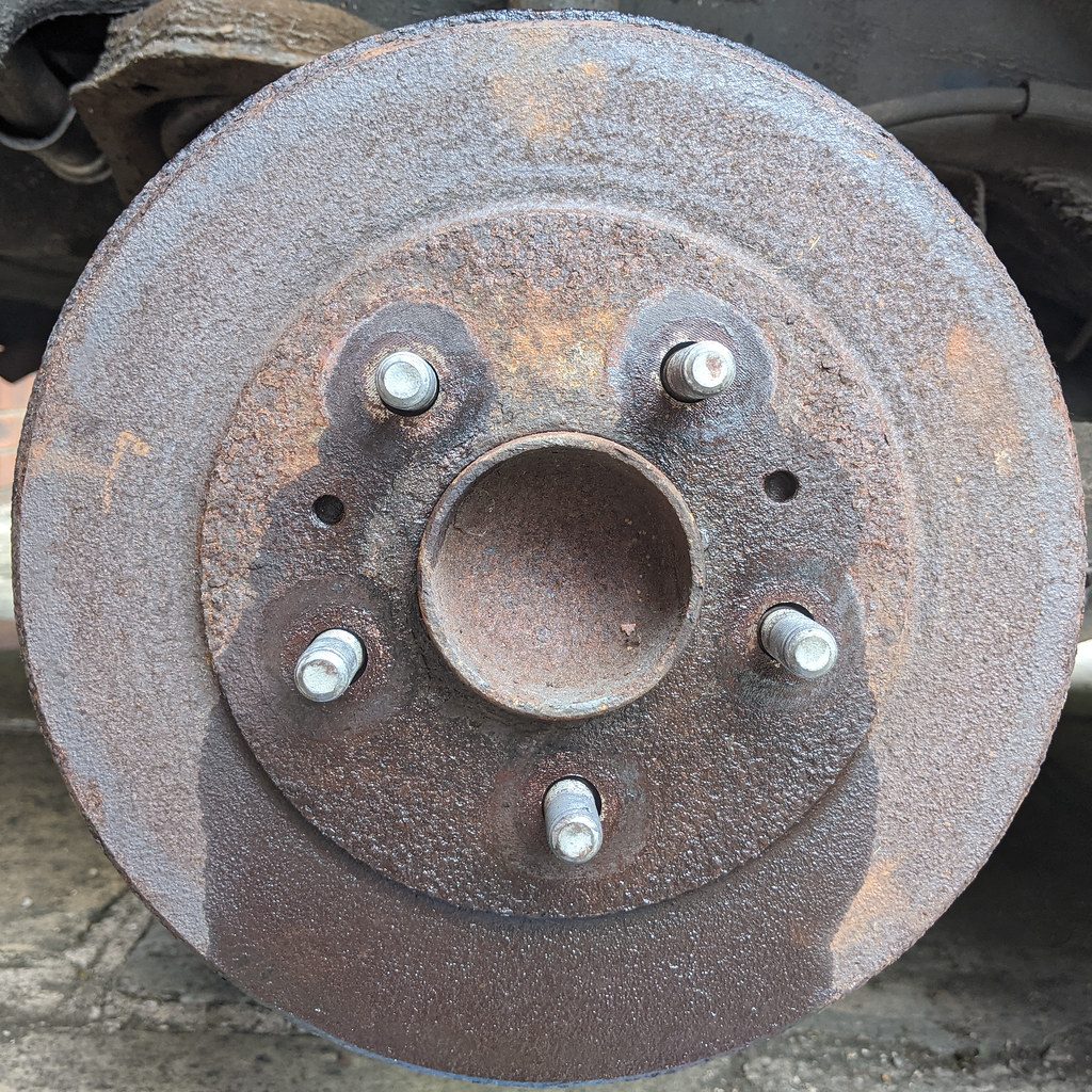 A worn brake pad held next to a new one